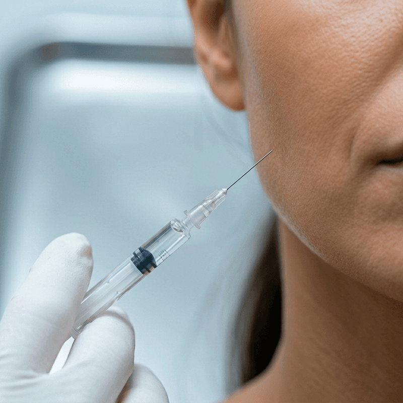 Seringa de botox próxima ao rosto representando procedimentos invasivos